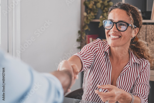 Smiling caucasian female hr manager handshake hire male candidate at job interview make good first impression, happy mixed race client shake hand of bank broker, respect, business agreement concept. photo