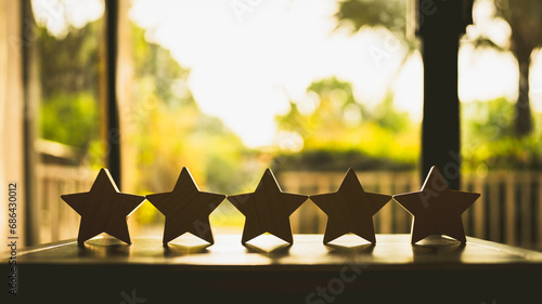 Businessman hand picking up model star on wooden table, Five star shape. The best excellent business services rating customer experience concept. photo