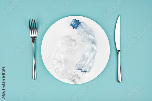 Bottle on the plate and other plastic waste on blue background photo