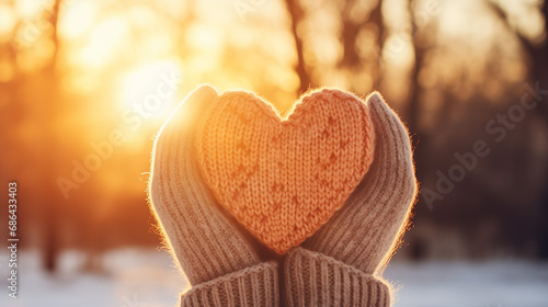 woman hands in winter gloves heart symbol shaped and feelings concept with sunset light winter