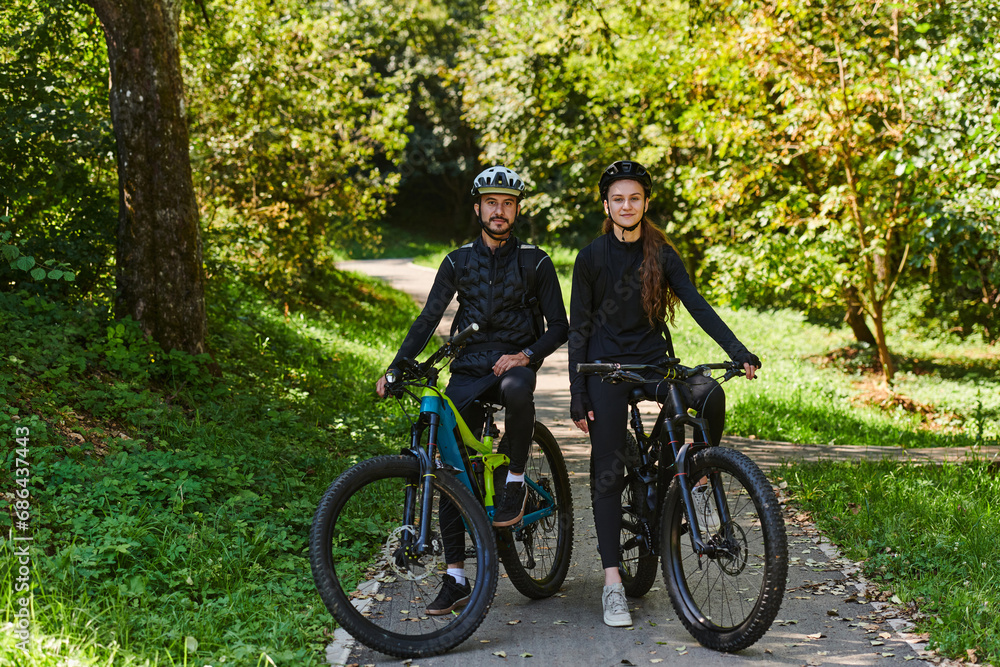 Naklejka premium A blissful couple, adorned in professional cycling gear, enjoys a romantic bicycle ride through a park, surrounded by modern natural attractions, radiating love and happiness
