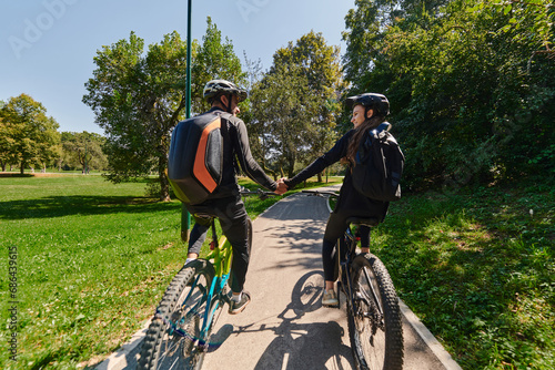 A sweet couple  adorned in cycling gear  rides their bicycles  their hands interlocked in a romantic embrace  capturing the essence of love  adventure  and joy on a sunlit path