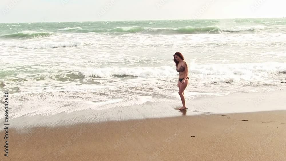 Hispanic Woman In Bikini Standing On Sandy Beach With Cold Wind And Waves Kneeling In Water
Hispanic Woman In Bikini Standing On Sandy Beach With Cold Wind And Waves Kneeling In Water