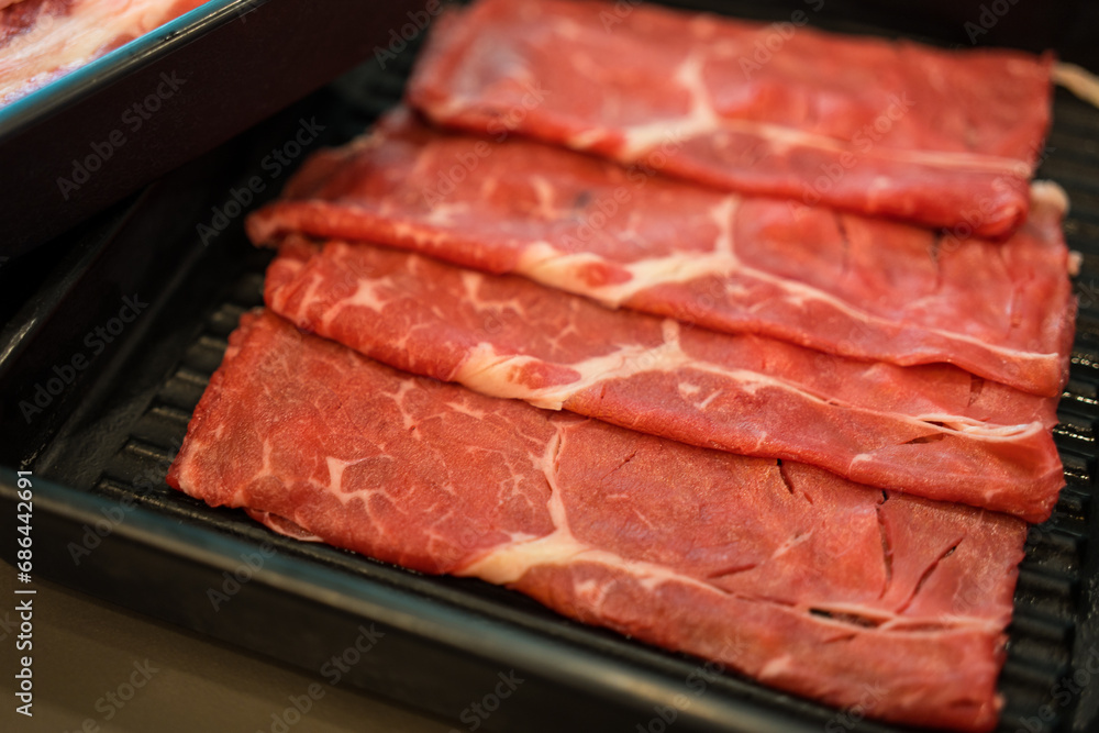 Fresh beef raw sliced with marbled texture served on black tray for Sukiyaki and Shabu
