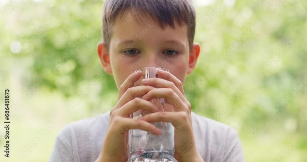 Thirsty child boy drinking water from glass outdoors in hot sunny day Thirsty child boy drinking water from glass outdoors in hot sunny day