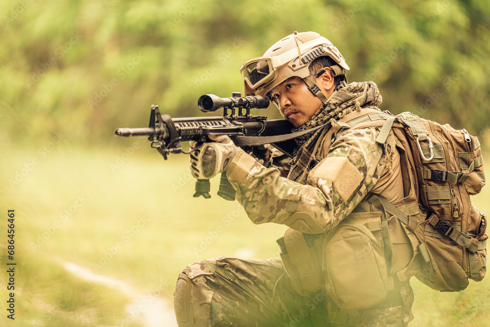 American soldier from the Army Sitting and aiming an M16 rifle, wearing camouflage, vision goggles, and military equipment. Have skills in war Ready to fight with enemies in dangerous battlefields.