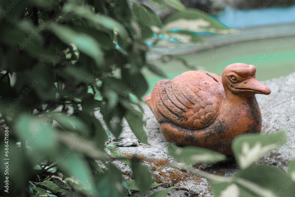 Brown duck statue sitting near water pond in park Brown duck statue sitting near water pond in park