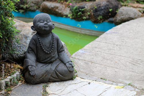 Statue of monk near small bridge near river