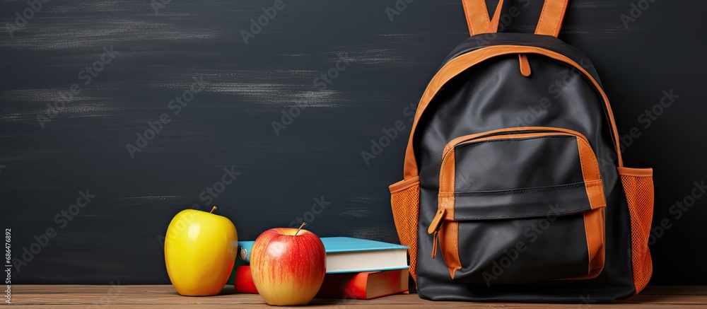 Chic backpack with school supplies on wooden table near chalkboard.