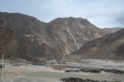 Valley between mountains on a cloudy day. A Dried river trains of Shyok river in Nubra Valley in Ladakh Region of Indian Himalayan territory .A Barren landscape of Cold dessert in Himalaya Valley .