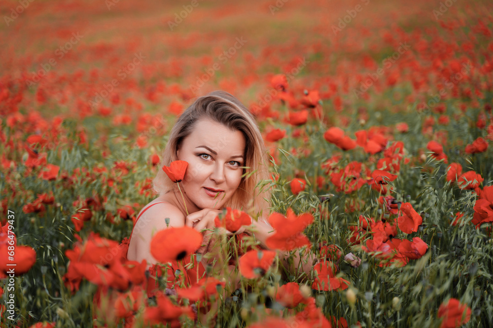 Naklejka premium Happy woman in a red dress in a beautiful large poppy field. Blond sits in a red dress, posing on a large field of red poppies