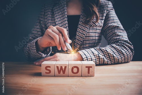 Businesswoman with SWOT text on wooden cube block. Swot analysis strategy for business plan and growth, Teamwork brainstorming vision and goal, evaluate work, planning technique operations concept. photo