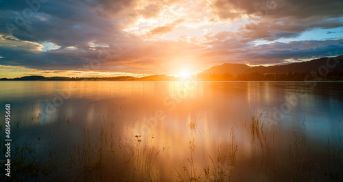 A peaceful waterfront with serene reflections under a bright  sunny sky.