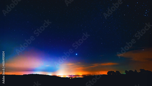 Silhouetted landscape beneath a starry sky with aurora borealis