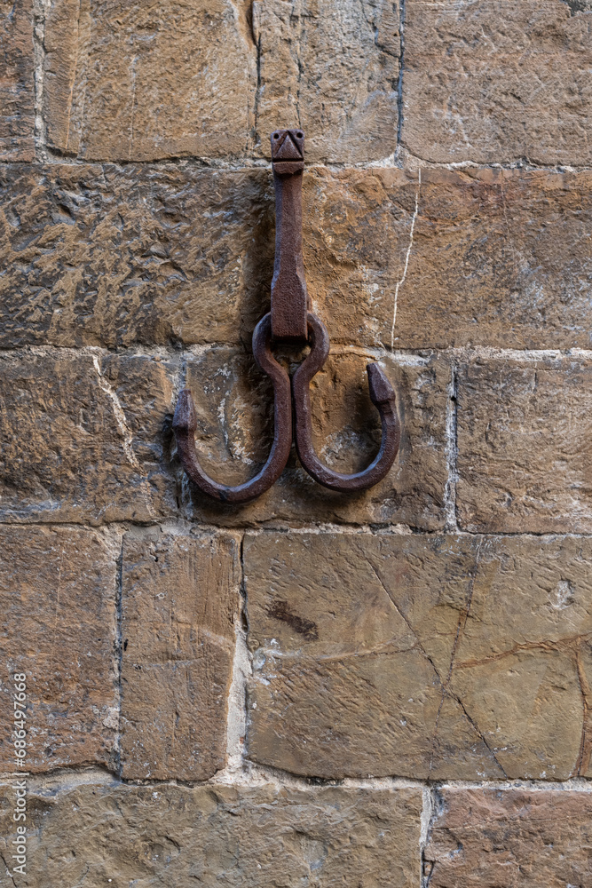 Rusted metal hooks attached to the exterior of an Italian building