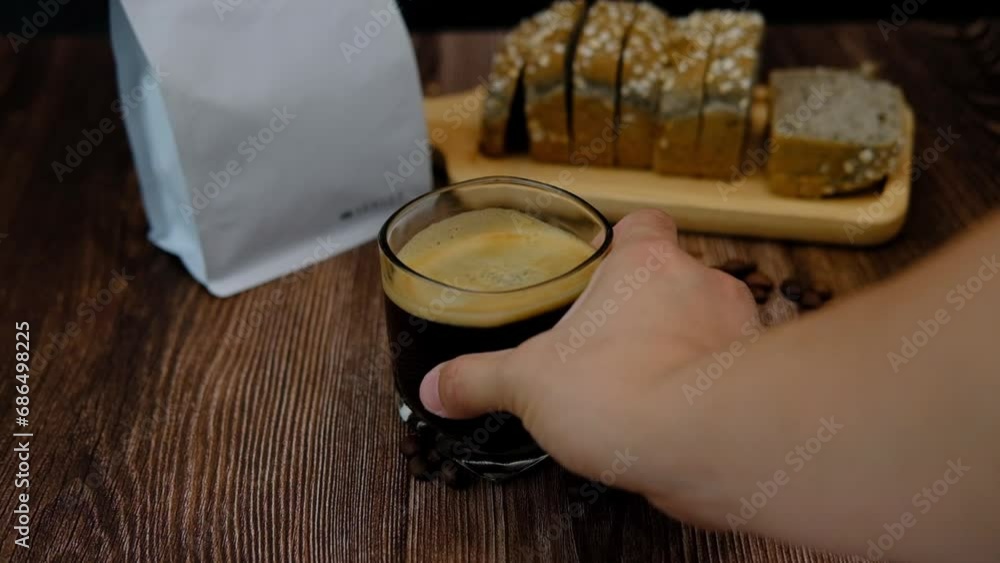 Male hand shaking a black coffee mug with moving crema. Male hand shaking a black coffee mug with moving crema.