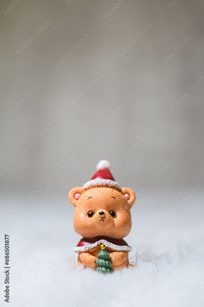 Small and cute Teddy Bear toy wears a Santa hat and cardigan with bokeh background. Winter and Christmas concept. Xmas decoration. Selective focus.