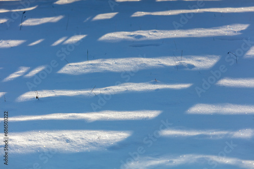 Shadow from a wooden fence on the snow in winter