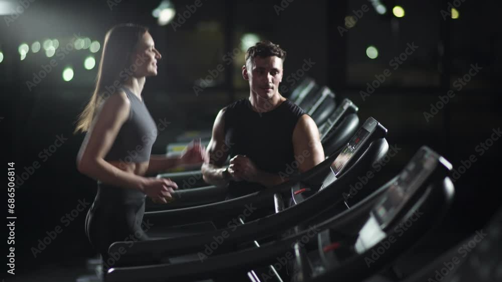 Wellness, young woman running on a treadmill, training with a coach, perform aerobic exercise and endurance training in the gym, nightlife. Wellness, young woman running on a treadmill, training with a coach, perform aerobic exercise and endurance training in the gym, nightlife.