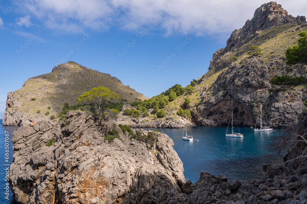 Beautiful views of the coastline at Port de Soller, with three yachts in a quiet harbour. on the island of Mallorca, Spain, Mediterranean Sea