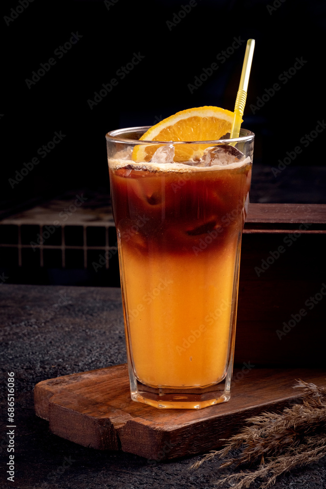 Orange coffee in a glass cup. Refreshing Cold Americano coffee with orange juice on a black background. Orange coffee in a glass cup. Refreshing Cold Americano coffee with orange juice on a black background.