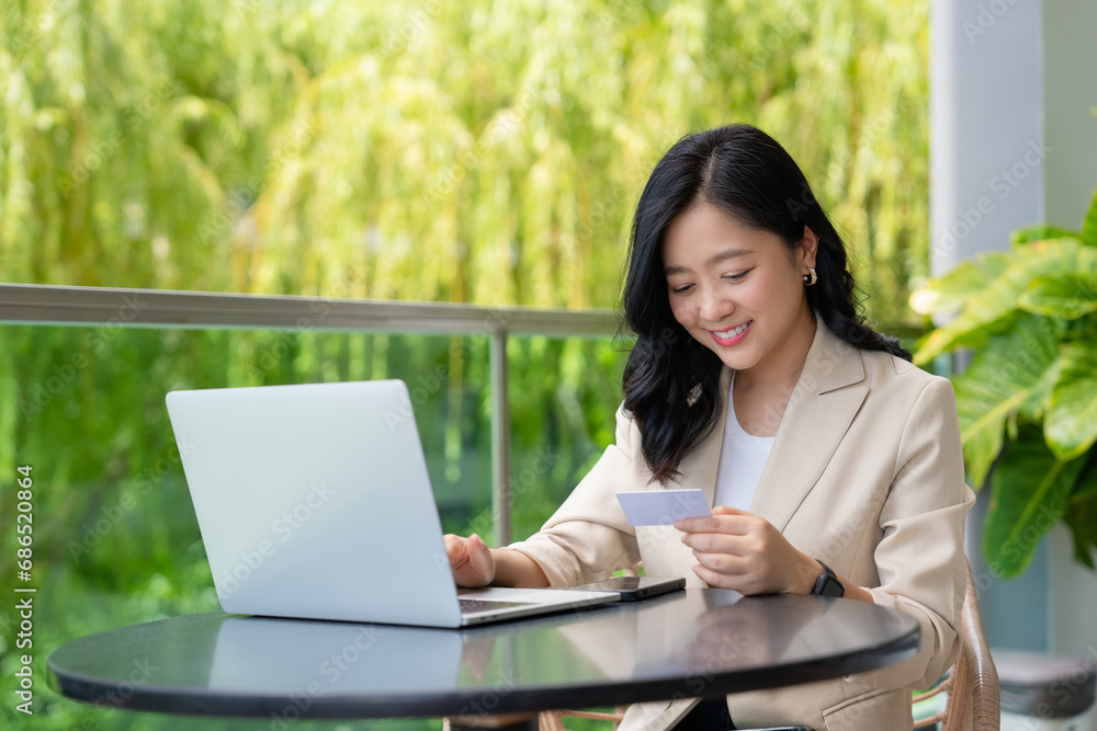 Young attractive happy Asian woman is using tablet for shopping and paying online by credit cards in her hand Young attractive happy Asian woman is using tablet for shopping and paying online by credit cards in her hand
