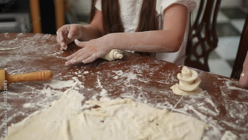 Family leisure time in the home kitchen in a modern house. The daughter learns to work with rolled out dough under the guidance of her mother Family leisure time in the home kitchen in a modern house. The daughter learns to work with rolled out dough under the guidance of her mother