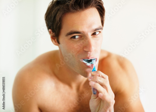 Bathroom, brushing teeth and man with dental hygiene, wellness and grooming routine for fresh breath. Person, home or guy with toothbrush, cleaning his mouth and morning with oral health or self care
