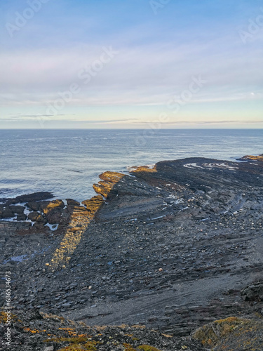 The rocky coast of the Barents Sea. Beautiful view of the rocks and the coast of the Rybachy and Sredny peninsulas, Murmansk region, Russia. The landscape is the harsh beauty of the north.