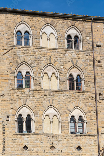 Gothic windows on stone facade at Priori square, Volterra, Italy