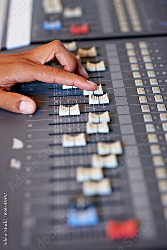 Hand, mixing and sound board in recording studio with dj, technology and media on desk. Music, deck and person editing with equipment for audio, production and moving switch on console for radio song