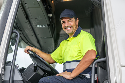 Cheerful male driver sitting in truck while looking at camera photo