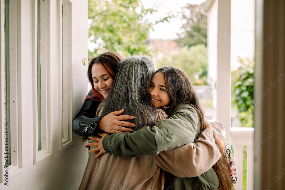 Happy multi-generation family embracing at entrance of house Happy multi-generation family embracing at entrance of house