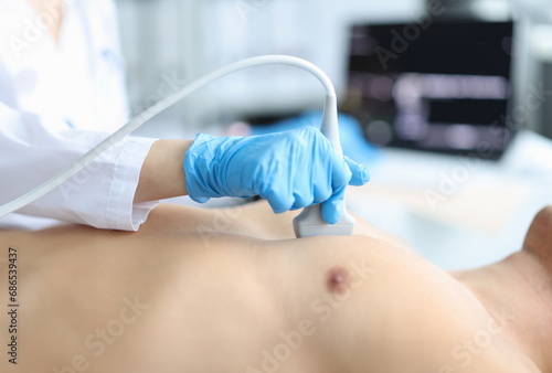 Doctor makes echocardiography of male patient using ultrasound probe pressing on patient chest. Ultrasound of heart in man concept photo