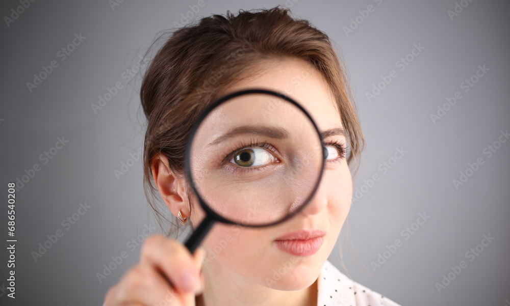 Inquisitive young woman looking through magnifying glass. Search for business ideas and new creative creative information Inquisitive young woman looking through magnifying glass. Search for business ideas and new creative creative information