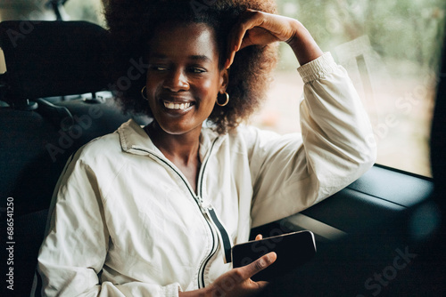 Smiling young woman holding smart phone while leaning on window of van