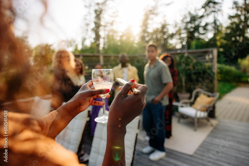 Woman holding drink glass while hosting dinner party with friends in back yard photo
