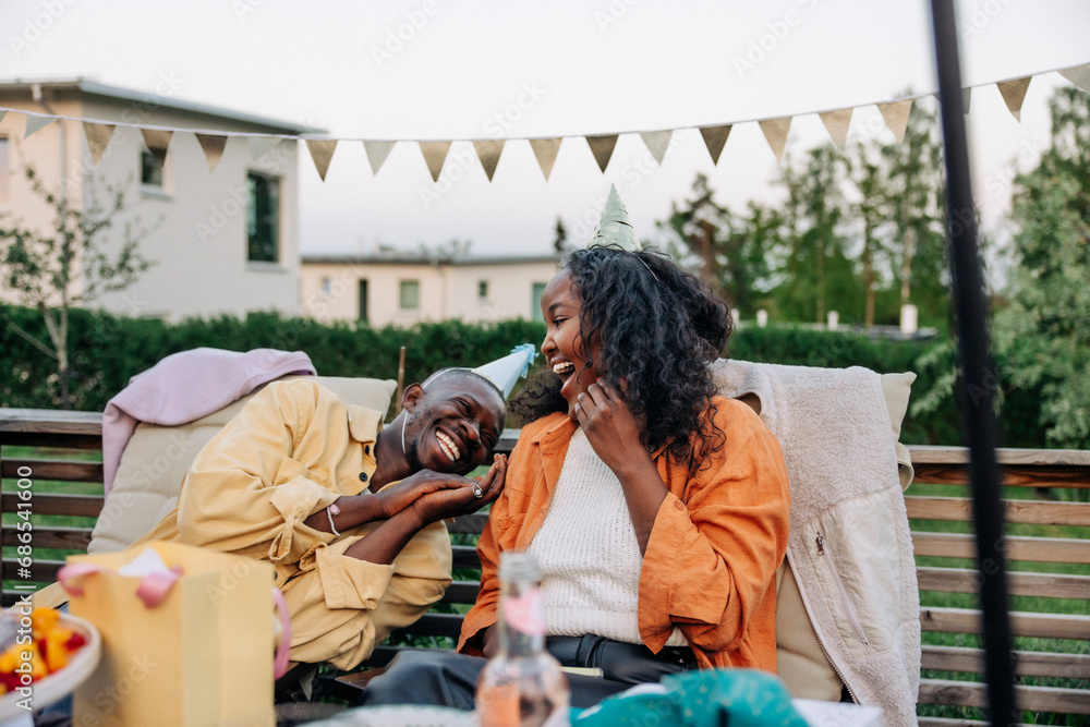 Young man laughing with female friend while sitting in back yard Young man laughing with female friend while sitting in back yard