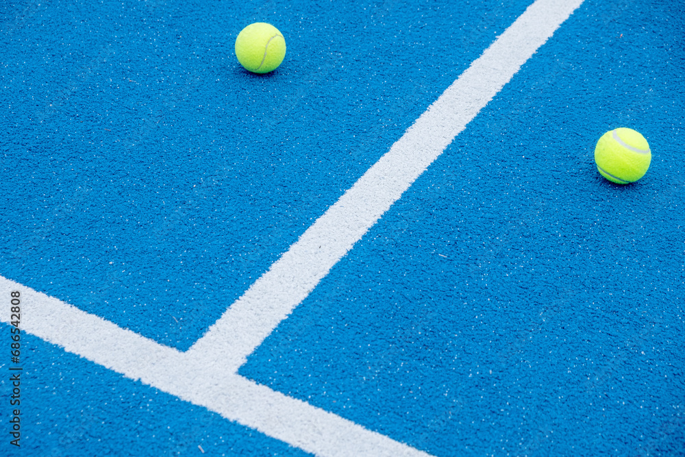 balls on a blue paddle tennis court with artificial grass