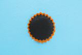 New dark black patch for car, bicycle or other transport tire hole repair on light blue table background. Pastel color. Closeup. Top down view.