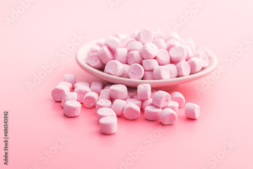 Mini sweet marshmallows candy on plate on pink background.