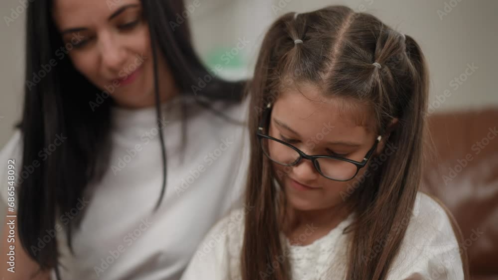 Close-up. Mom watches carefully as her daughter draws