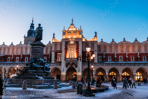 Krakow Christmas Market Square - before the sunset. Beautiful Sukiennice (Cloth Hall) and Adam Mickiewicz sculpture