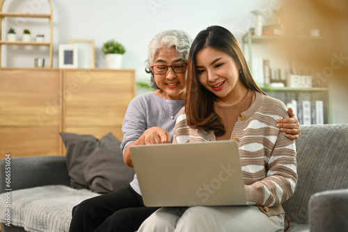 Happy mature mother and adult daughter using laptop surfing internet or shopping via internet at home © Prathankarnpap