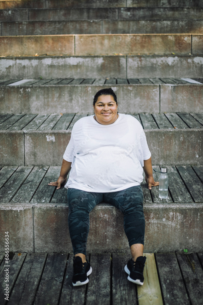 Portrait of smiling oversize woman relaxing on steps Portrait of smiling oversize woman relaxing on steps