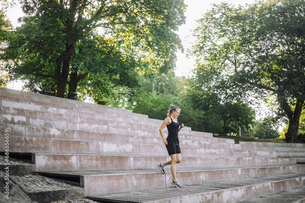Young woman moving down from steps at park Young woman moving down from steps at park