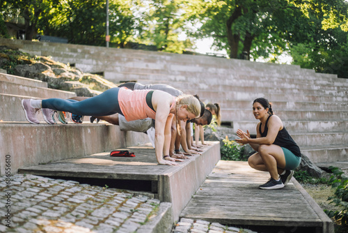 Female coach motivating team working out on steps photo