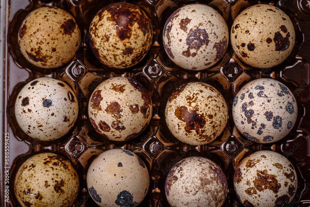 Raw quail eggs in a plastic box on a dark concrete background Raw quail eggs in a plastic box on a dark concrete background