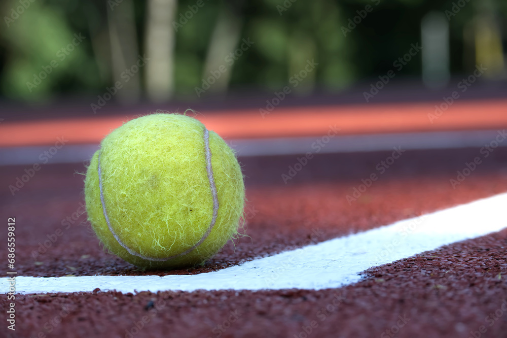 Wet tennis ball on clay court surface in low angle view