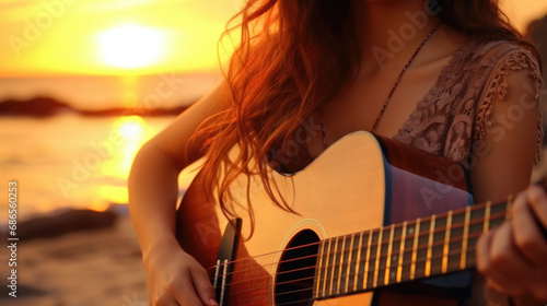 Beautiful romantic curly woman, with a guitar, sitting on the beach at sunset. Space for text